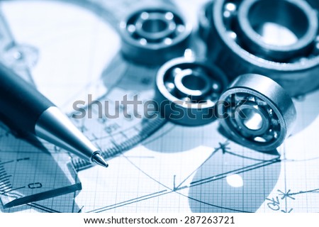 Engineering concept. Few ball bearings near ruler and pen on graph paper background