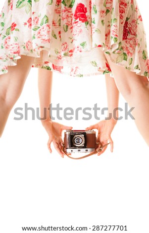 Woman's legs and hand, unusual back view of girl taking picture using vintage camera isolated on white background