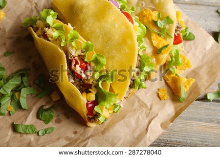 Tasty taco with greens on paper close up