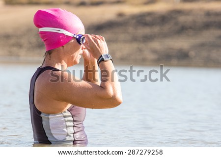 Female Triathlete swimming in a dam while training for a triathlon.
