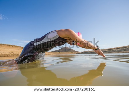 Close up wide angle view of a female triathlete diving into the water while training for a triathlon