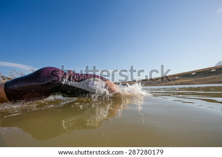 Close up wide angle view of a female triathlete diving into the water while training for a triathlon