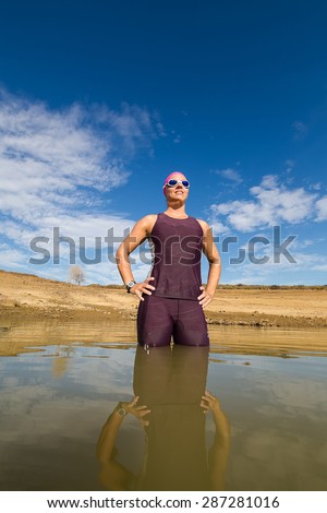 Close up wide angle view of a female triathlete standing waist deep in the water in a dam just before going to train for a triathlon.