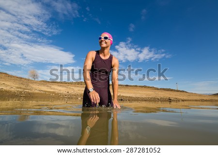 Close up wide angle view of a female triathlete standing waist deep in the water in a dam just before going to train for a triathlon.