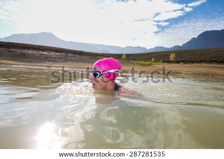 Wide angle close up image of a female triathlete swimming in a dam