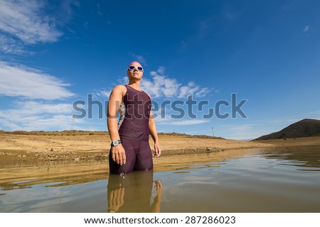Close up wide angle view of a female triathlete standing waist deep in the water before she is about to train for a triathlon.