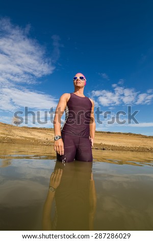 Close up wide angle view of a female triathlete standing waist deep in the water before she is about to train for a triathlon.