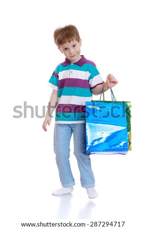 Little boy in striped t-shirt and jeans holding a shopping bag-Isolated on white background