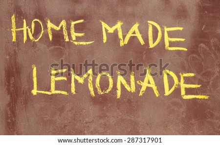 Written by hand creative inscription with chalk on a brown metal board sprinkled with many different colored dots - Homemade lemonade.