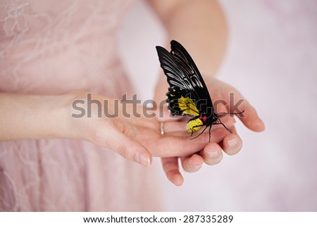 Beautiful exotic butterfly sitting on the girl hand