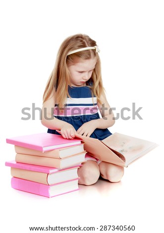 Cute long-haired Caucasian little girl reading a book sitting on the floor-isolated on white background