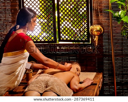 Young woman having oil Ayurveda spa treatment. Day outdoor.