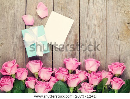 Valentines day greeting card, gift box and pink roses over wooden table. Top view