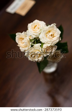 Small delicate bouquet of cream roses on a brown table