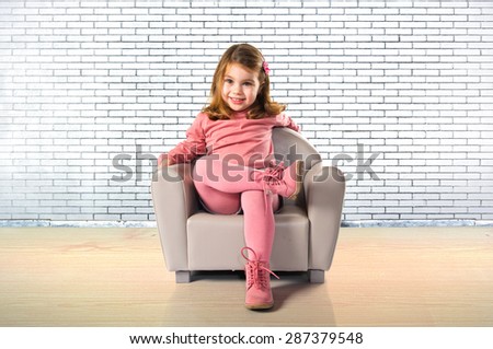 Little girl sitting on armchair