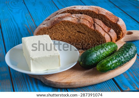 Freshly baked bread, cucumber and butter all for sandwich in rural or rustic kitchen on vintage wood table from above. Background