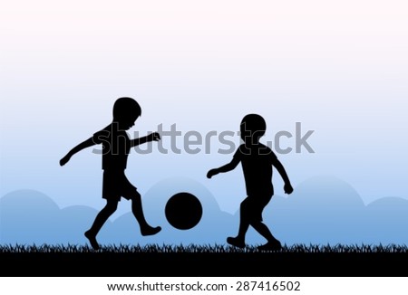 Two small boys kicking a ball on the grass