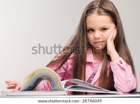 Happy little girl reading open book