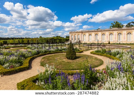 View of a corner of the garden in the Grand Trianon Palace on a sunny day with clouds and blue sky. A famous palace in the northwestern part of the Domain of Versailles, Paris, France Royalty-Free Stock Photo #287474882