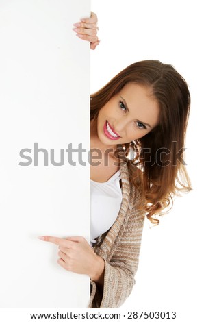 Beautiful happy woman pointing on blank board.