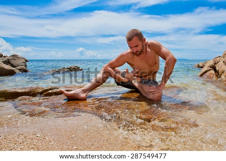 man doing yoga on the beach