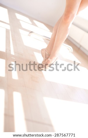 Low Angle View of Ballerina Wearing Ballet Slippers on Toes in Sunny Dance Studio