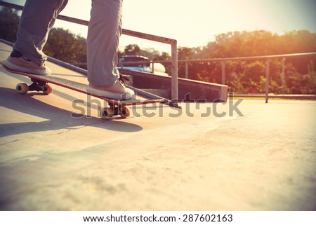 skateboarder legs riding skateboard at skatepark ramp