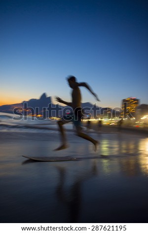 Action silhouette of Brazilian jumping onto skimboard on Ipanema Beach Rio de Janeiro Brazil at sunset