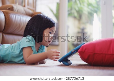 Candid picture of baby girl watching video on tablet 