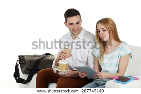Portrait of young happy couple with baggage, sitting on sofa. isolated on white
