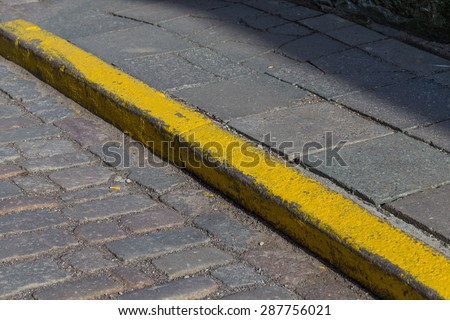 Yellow curb stone border in an old town road