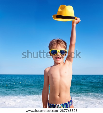 Happy child in sunglasses with yellow hat against sky background