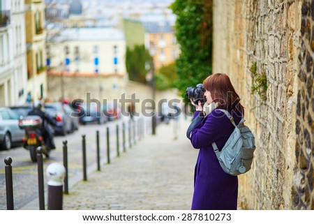 Beautiful young tourist in Paris, taking a photo on the street