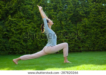 pretty woman doing yoga on green grass in summer park