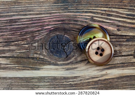 two vintage buttons on aged textured surface of ol boards
