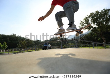 skateboarder legs doing a ollie at skatepark