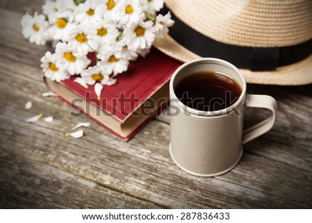 Coffee, daisies and a book on a wooden background Royalty-Free Stock Photo #287836433