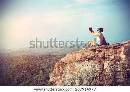woman hiker taking photo with digital tablet at mountain peak,vintage effect