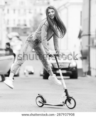 girl on a skateboard scooter in the city 
