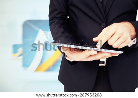 Mid section of a businessman touching digital tablet against digital blue background with screens including graphs