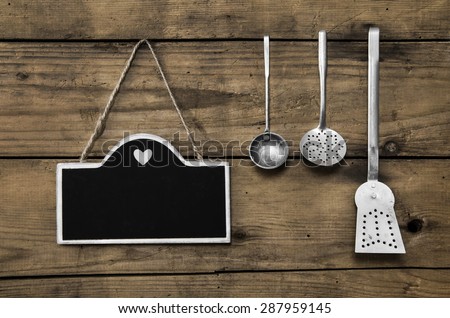 Wooden old kitchen background with old kitchenware, blackboard and spoons for cooking fans.