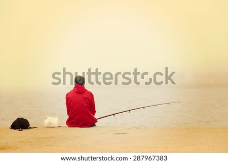 A lonely fisherman sitting and fishing at the dock. Image has a vintage effect.