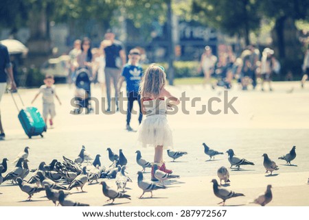 A girl feeding pigeons in the mall. Image has a strong vintage effect.