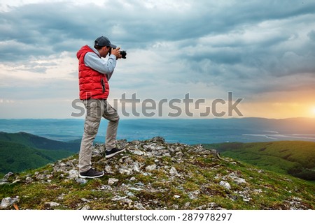 Photographer is taking a picture of  landscape in mountains