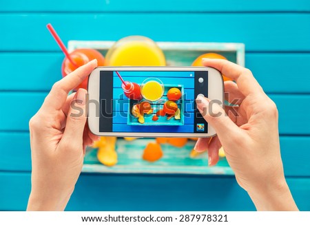 woman taking picture of vintage tray with fruits on her smartphone. Top view