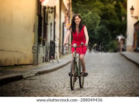 Beautiful brunette girl on a vintage bike, old town street