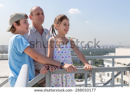 Grandfather with grandson and granddaughter admire the city view from the roof