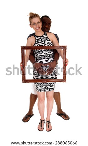 Pregnant woman holding a picture frame over her tummy and the
hands of her African American man, isolated for white background.
