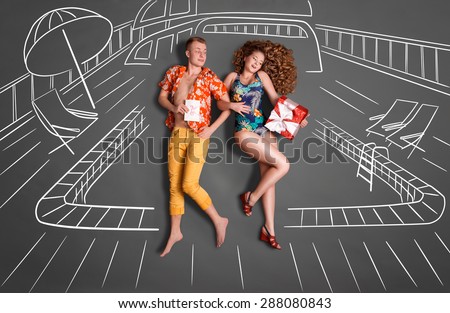 Love story concept of a romantic couple against chalk drawings background. Young couple on vacation sharing gifts against a swimming pool background.