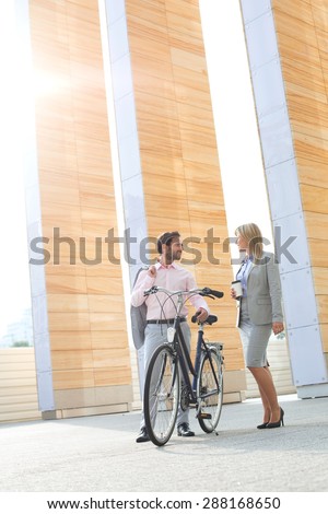 Businesspeople with bicycle conversing outside building Royalty-Free Stock Photo #288168650